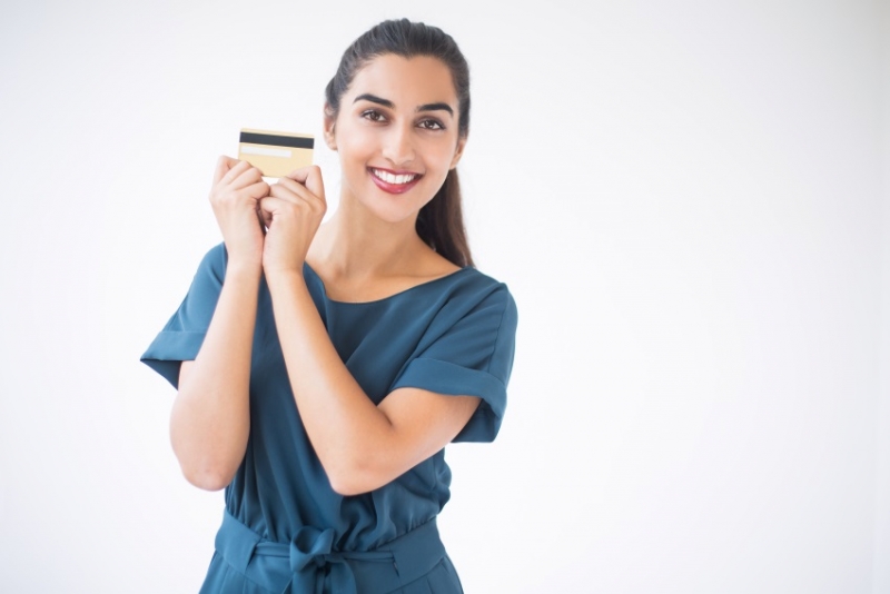 A woman holding a credir card and smiling.